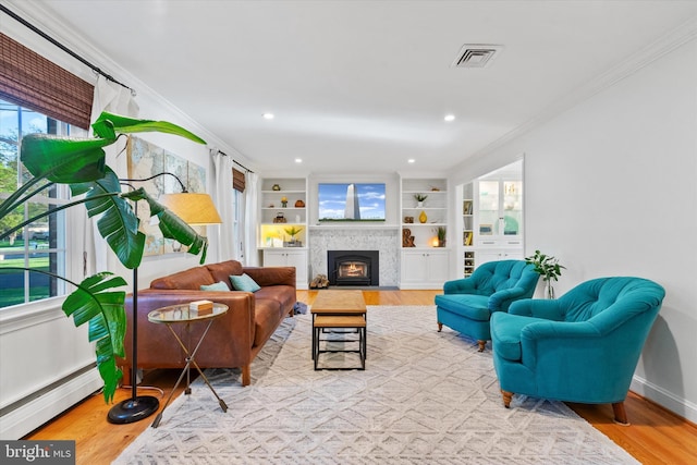 living room with visible vents, wood finished floors, crown molding, and a baseboard radiator