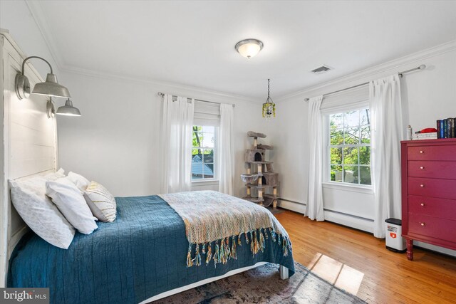 bedroom with wood finished floors, visible vents, ornamental molding, and multiple windows