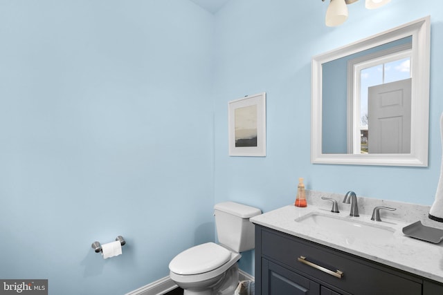 half bathroom with toilet, vanity, and baseboards