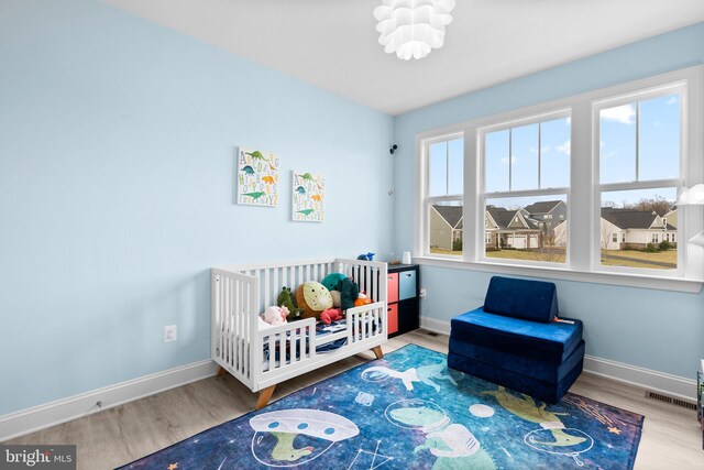bedroom featuring wood finished floors, visible vents, and baseboards