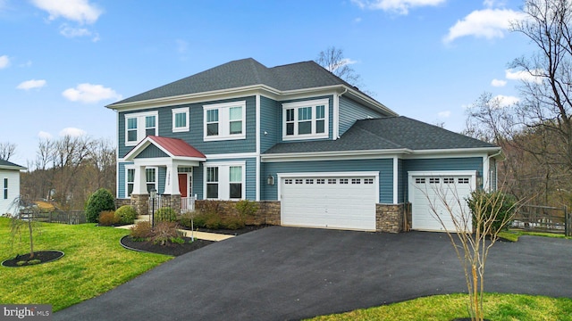 view of front facade featuring a front lawn, aphalt driveway, stone siding, a shingled roof, and an attached garage