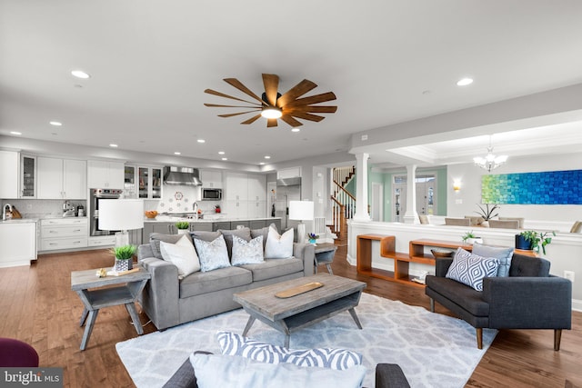 living area featuring recessed lighting, wood finished floors, stairway, and ceiling fan with notable chandelier