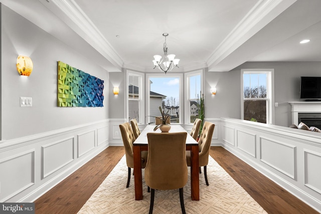 dining room with a wainscoted wall, an inviting chandelier, dark wood-type flooring, and ornamental molding
