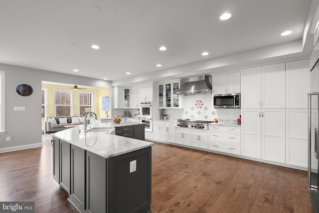 kitchen featuring a sink, stainless steel appliances, white cabinets, wall chimney exhaust hood, and dark wood-style flooring