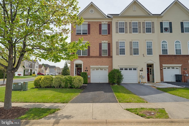 view of property featuring brick siding, a front lawn, driveway, and an attached garage