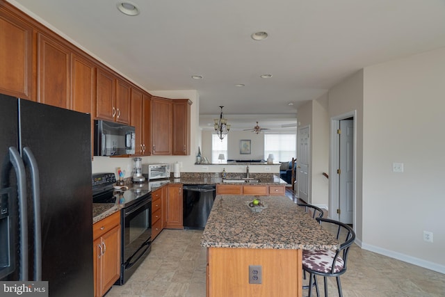 kitchen with brown cabinets, a sink, a breakfast bar, a center island, and black appliances