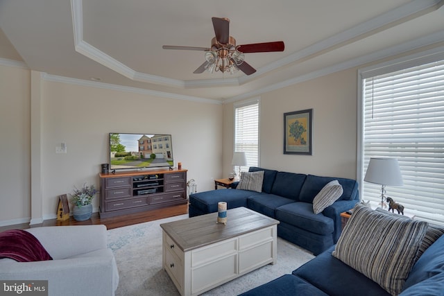 living area with light wood-style flooring, ceiling fan, crown molding, and a tray ceiling