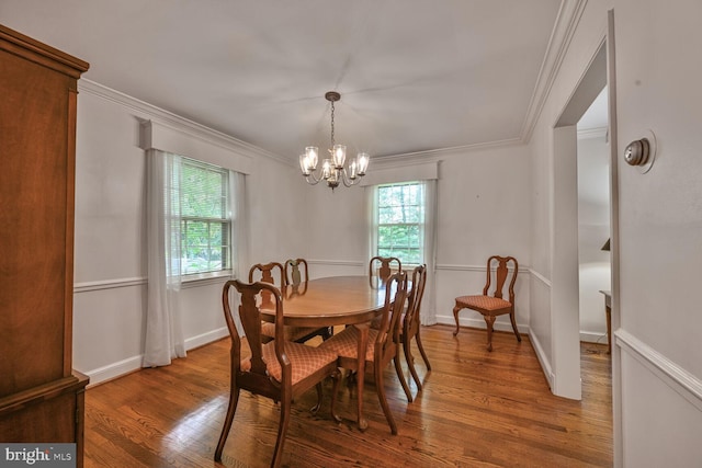 dining area featuring a chandelier, wood finished floors, crown molding, and baseboards