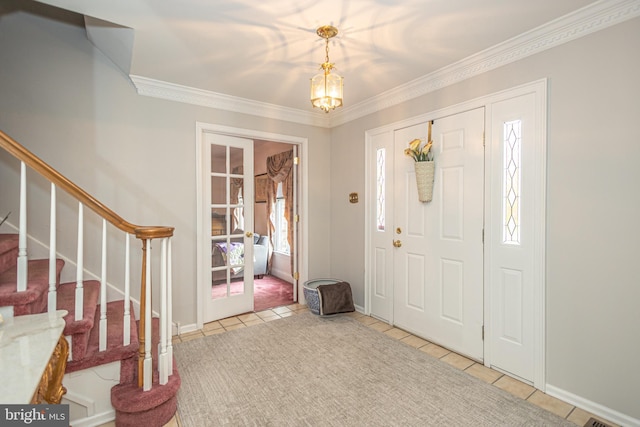 entrance foyer with a chandelier, ornamental molding, tile patterned flooring, and stairs