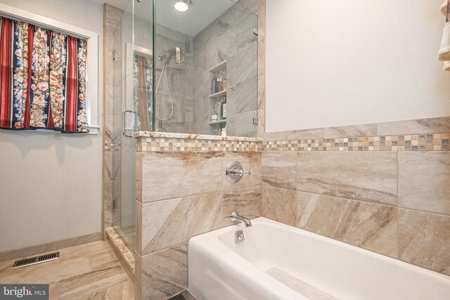 bathroom with a shower stall, visible vents, baseboards, and a tub