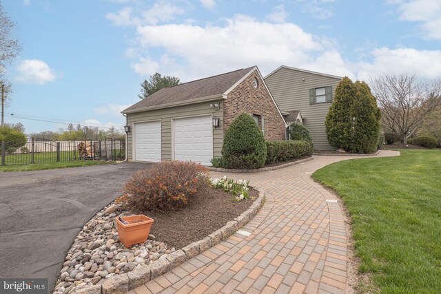 view of side of property with a lawn, an attached garage, driveway, and fence