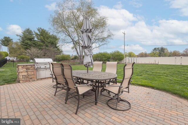view of patio / terrace with outdoor dining space, an outdoor kitchen, a fenced backyard, and area for grilling