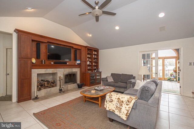 living area with light tile patterned floors, vaulted ceiling, a ceiling fan, and a fireplace