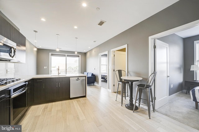 kitchen with a sink, light wood-style floors, visible vents, light countertops, and appliances with stainless steel finishes