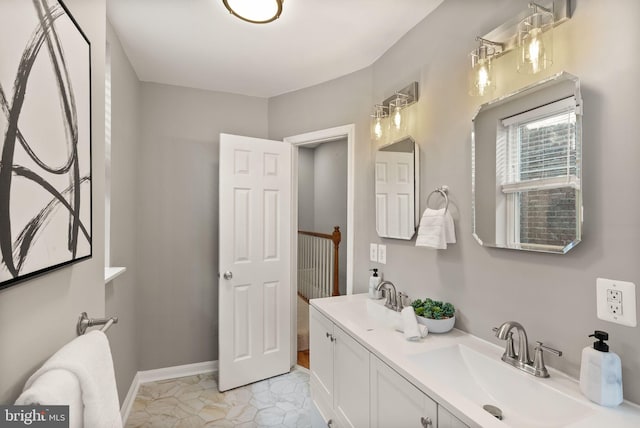 bathroom with double vanity, baseboards, and a sink