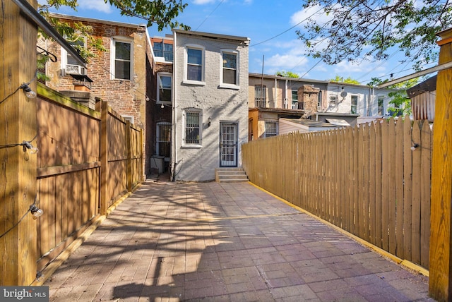 back of property with brick siding, a patio area, entry steps, and fence private yard