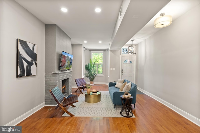 living area with baseboards, wood finished floors, a fireplace, and recessed lighting