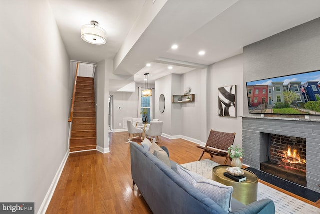 living area with baseboards, recessed lighting, wood finished floors, stairway, and a fireplace