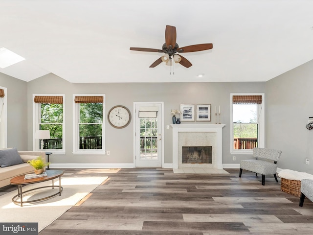 109 Rock Creek Ct, Frederick, MD 21702 - living room with a tiled fireplace, ceiling fan, baseboards, a skylight, and wood finished floors