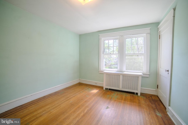 spare room with hardwood / wood-style flooring, baseboards, and radiator