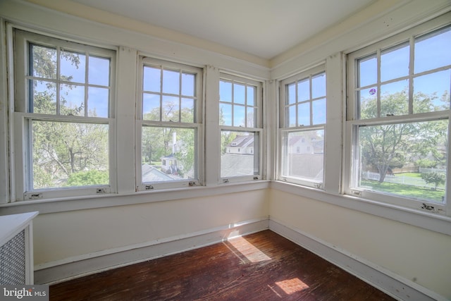 unfurnished sunroom featuring baseboards, wood finished floors, and a wealth of natural light
