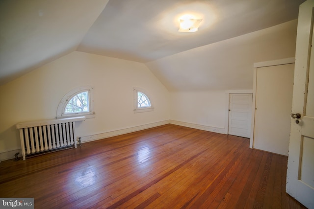 bonus room with radiator heating unit, wood-type flooring, and vaulted ceiling