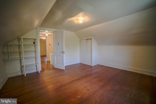 additional living space featuring baseboards, vaulted ceiling, and hardwood / wood-style floors