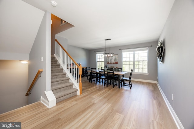 dining room with stairs, baseboards, a chandelier, and wood finished floors