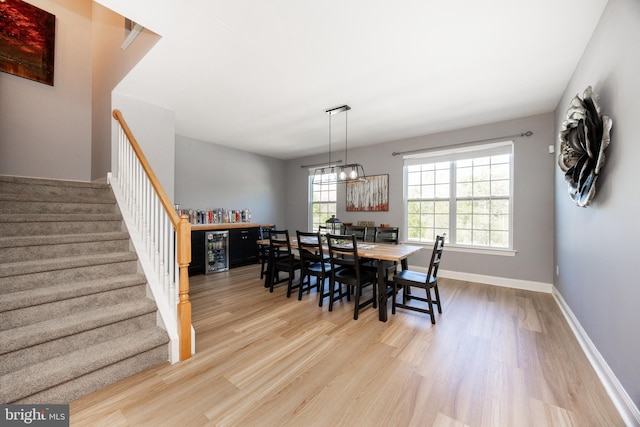 dining room with baseboards, stairs, wine cooler, and wood finished floors