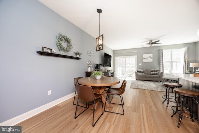dining area featuring baseboards, ceiling fan, light wood-style flooring, and lofted ceiling