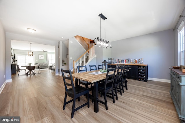 dining area with stairway, baseboards, and light wood-style flooring