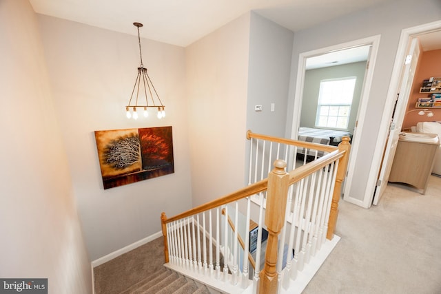 staircase with carpet floors, baseboards, and a chandelier