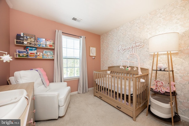 bedroom featuring visible vents, baseboards, wallpapered walls, a nursery area, and carpet flooring