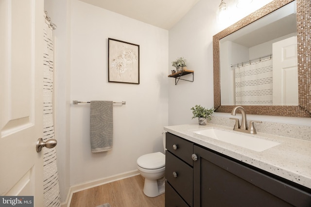 full bath with toilet, baseboards, wood finished floors, and vanity