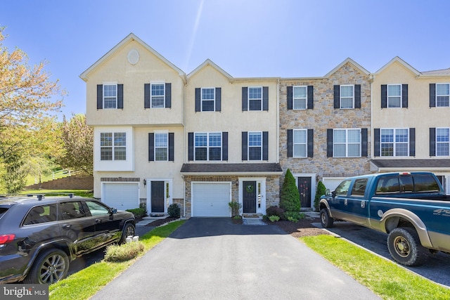 view of property with a garage, driveway, stone siding, and stucco siding