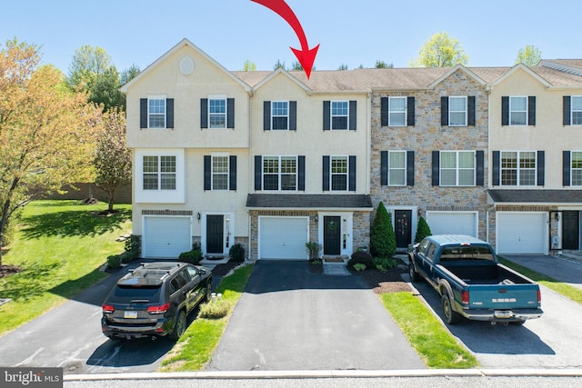 view of property featuring an attached garage, driveway, stucco siding, and stone siding