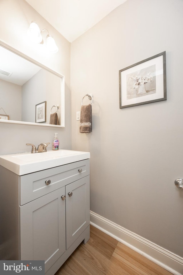bathroom with baseboards, visible vents, wood finished floors, and vanity