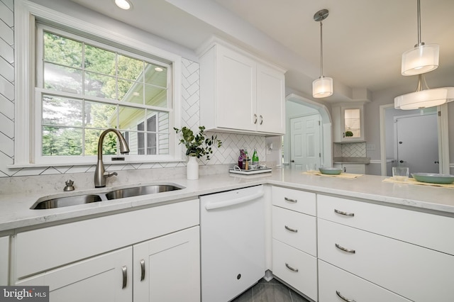 kitchen with decorative backsplash, plenty of natural light, dishwasher, a sink, and white cabinets