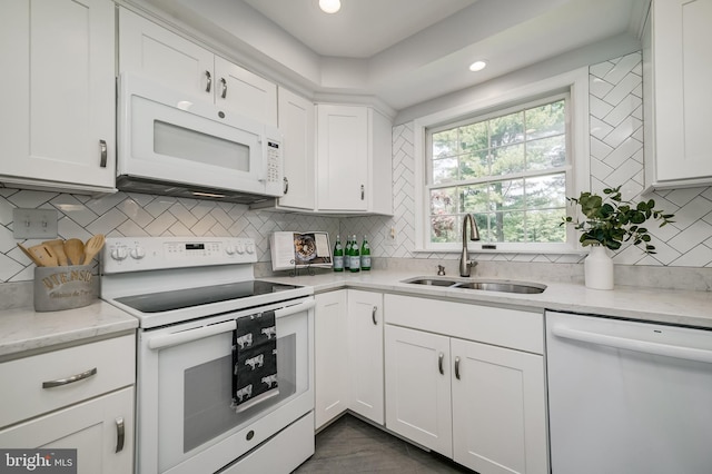 kitchen featuring white appliances, white cabinets, a sink, and tasteful backsplash