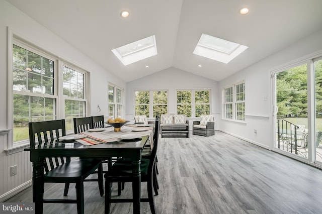 sunroom with recessed lighting, a wooden deck, wood finished floors, and vaulted ceiling with skylight