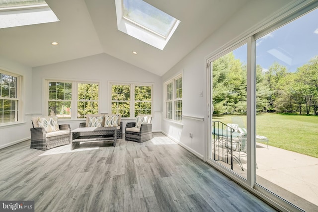 sunroom with baseboards, wood finished floors, and vaulted ceiling with skylight