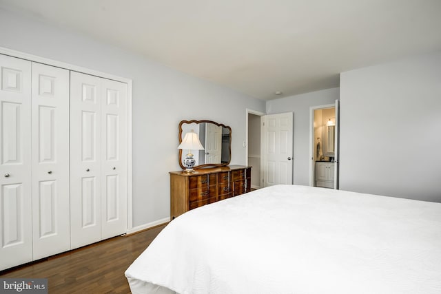 bedroom with a closet, baseboards, ensuite bath, and dark wood-type flooring