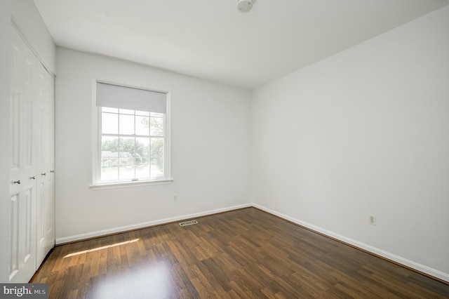 unfurnished bedroom featuring baseboards, visible vents, wood finished floors, and a closet