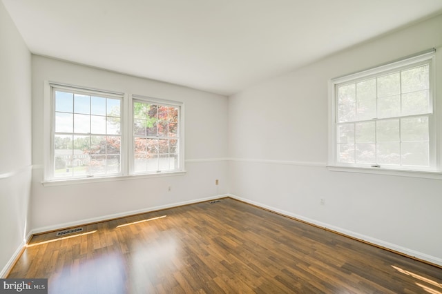 unfurnished room with baseboards, wood finished floors, and visible vents