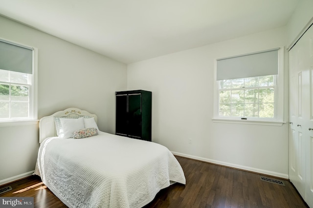 bedroom featuring baseboards, visible vents, wood finished floors, and a closet
