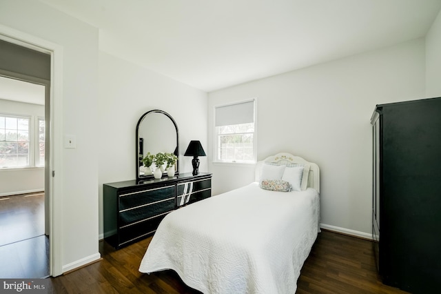 bedroom with dark wood-style flooring, baseboards, and multiple windows