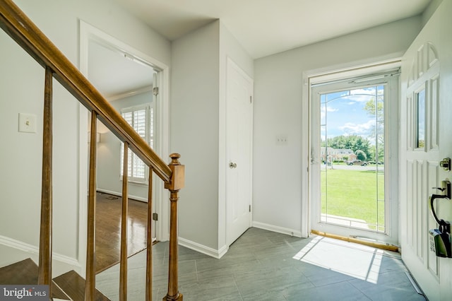 foyer entrance with a healthy amount of sunlight, baseboards, and stairway