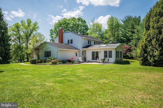 back of house featuring a yard, a patio, and a chimney