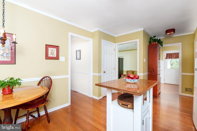kitchen featuring baseboards, light wood-type flooring, visible vents, and crown molding