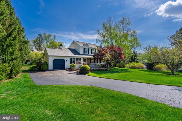 view of front of home featuring a chimney, aphalt driveway, a front yard, and an attached garage